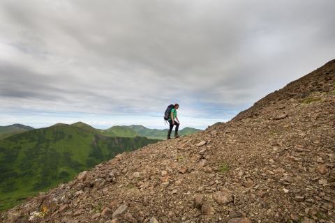 woman with a backpack hikes up a rocky slope