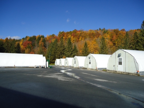 A row of white buildings amidst a mountainous forest setting