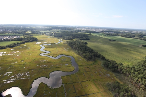 Green marshland, a wandering river and human-made canals are visible in this aerial of Cape May National Wildlife Refuge.