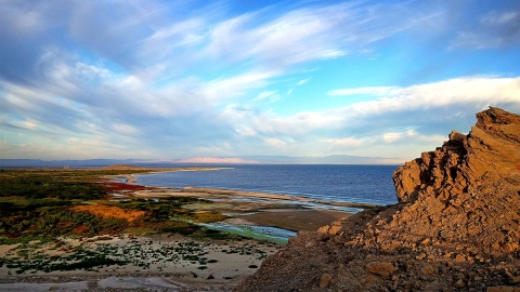 a rocky beach under a partly cloudy sky
