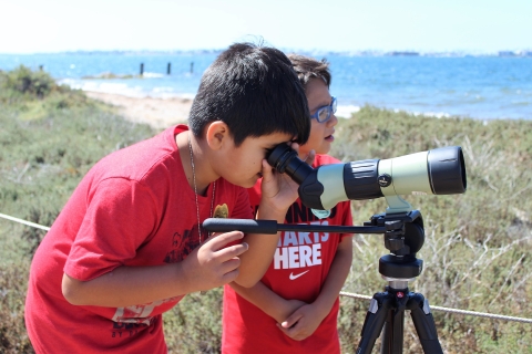 Two young boys use a spotting scope 