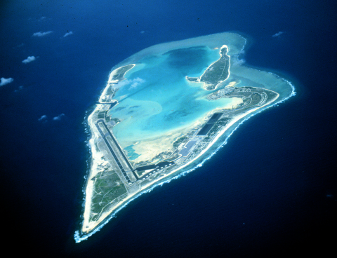 An aerial view of Wake Atoll. The ocean surrounds a collection of islands that jut south like an arrowhead. In the center is a bright blue bay. 