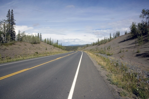 View of a two-lane highway cutting through Alaskan wilderness.