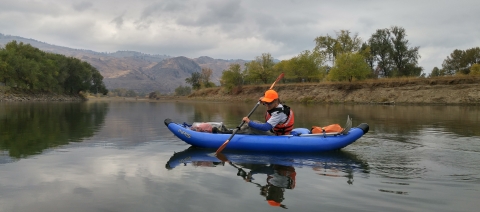 Person in a blue inflatable kayak on a calm river
