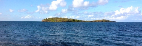 A small island in the distance surrounded by ocean water. 