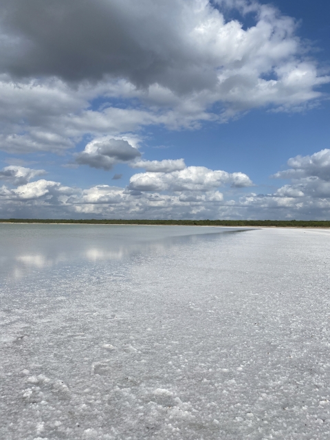 Floor bed covered with salt and water surrounded by semi-covered cloud. 