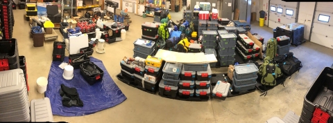 field gear organized in plastic boxes stored in a warehouse