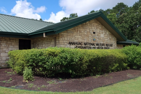 The Anahuac National Wildlife Refuge visitors center is shown with bushes in front.