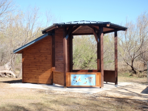 A brown wooden structure with a nature painting on one side is shown.