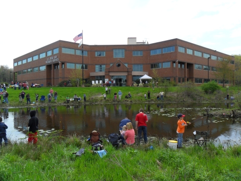 People fishing on a pond in front of a large brick building. Text on building U.S. Fish and Wildlife Service