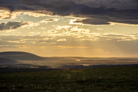 Sun rays through clouds light up the coastal plain north of the Brooks Range, viewed from the Dalton Highway.