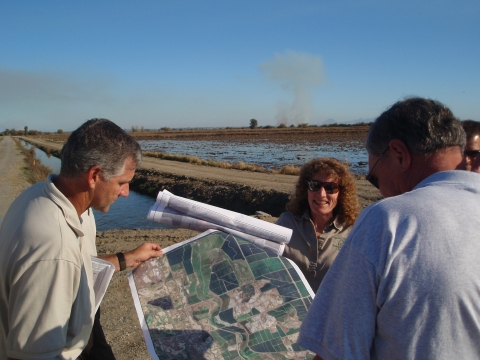 Three partners look at a map of a wetland restoration project