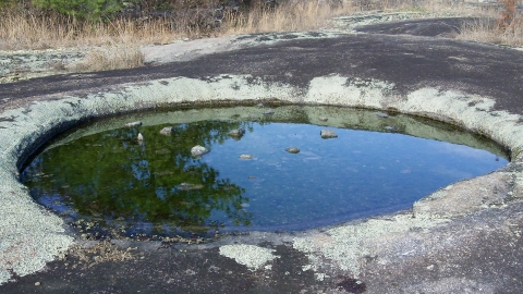 shallow pool of water on a smooth rocky landscape