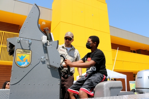 A man shows a boy the controls of a boat on land
