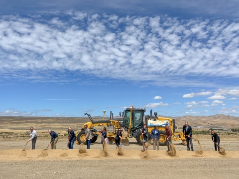 a group of people with shovels making a hold with a tractor behind them