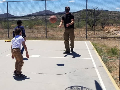 2 kids and adult play basketball on outside court
