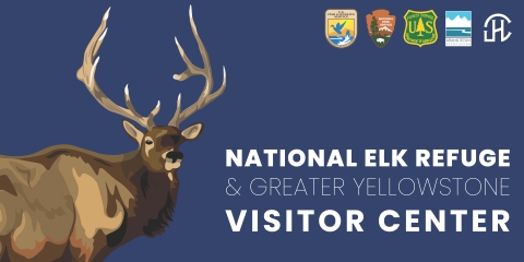A blue rectangular sign that reads "National Elk Refuge & Greater Yellowstone Visitor Center" with an elk rendering and a variety of agency logos in the upper right corner