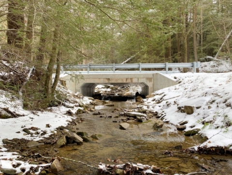 Culvert after with a short bridge and large opening underneath. Water flows freely.
