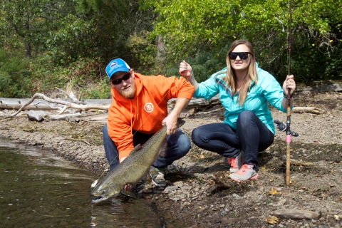 Two Columbia River anglers along the shoreline with a large Pacific salmon