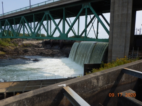 Dam with bridge overhead. Fish passage structures can be seen in the foreground