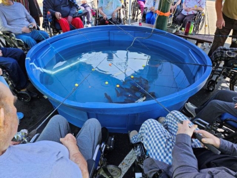 Elderly people gathered around a blue tub with fishing poles