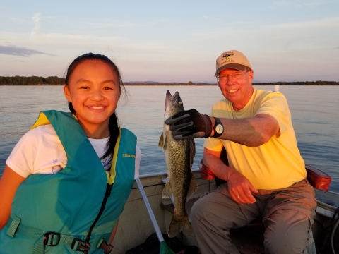 The author and his daughter in a fishing boat holding a fish