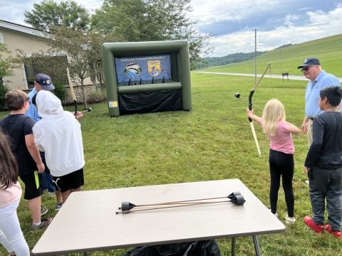 USFWS volunteers assisting kids with shooting archery at blow up targets
