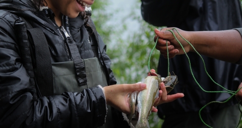 a person smiling holding fish in hand
