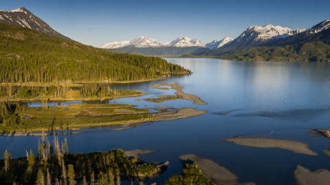 A stunning landscape of blue lake, green forest and snow-capped mountains at Kenai National Wildlife Refuge in Alaska.