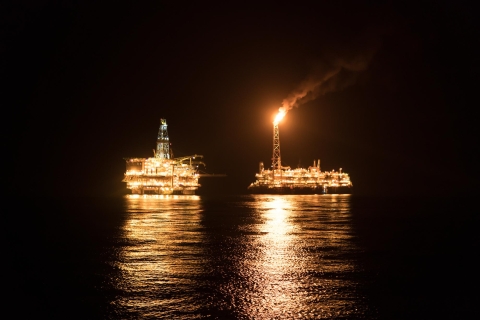 Offshore vessels at night with bright lights on.