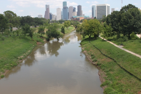 the skyline of the city of Houston rises above Buffalo Bayou