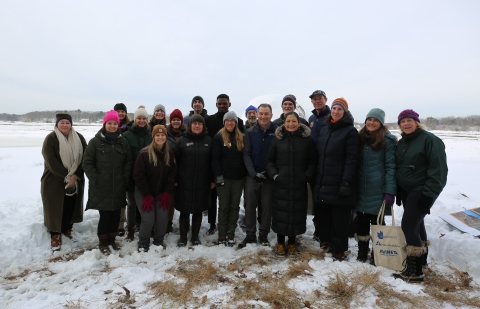 A smiling group stands in a snowy marsh