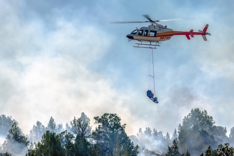 A device hangs by a rope from a helicopter.