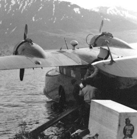 Seaplane being loaded by three people