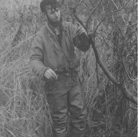 Man in field by tree branch