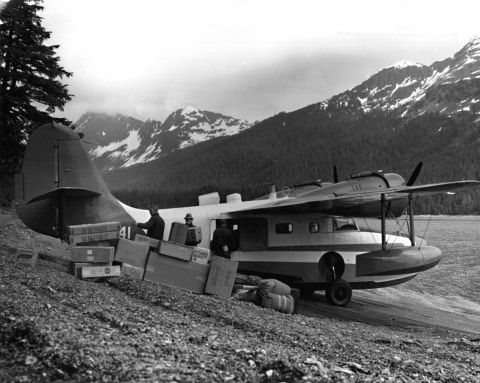 Two people off-loading U.S. Fish and Wildlife Service Grumman N741 food supplies
