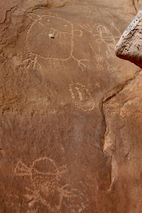 Red brown rock face with carvings of figures and other shapes