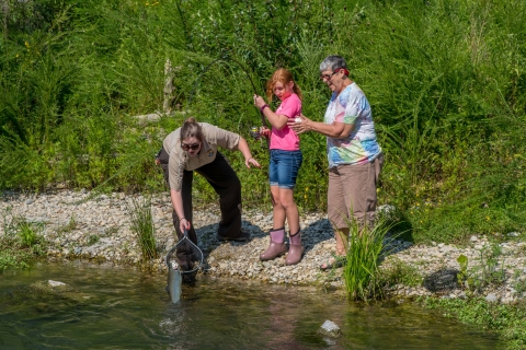 Service employee netting trout caught by young girl