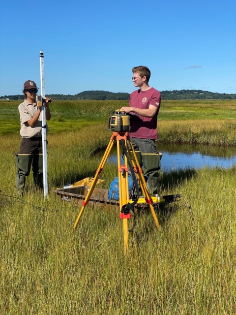 Image of two technicians in the salt marsh using instruments