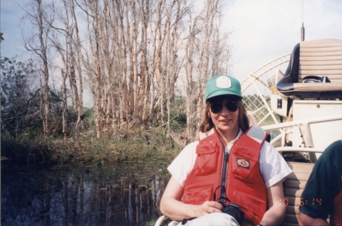 Woman wearing life jacket and riding a boat through a swamp
