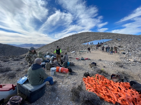 A team of people from the USFWS, Nevada Department of Wildlife, and Fraternity for the Desert Bighorn working together to construct an artificial spring (guzzler) atop a mountain.