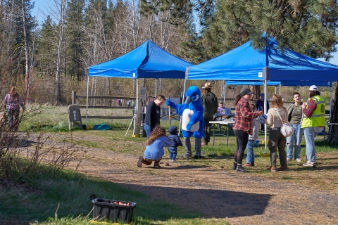 A small child interacts with the Puddles Blue Goose mascot during a special event
