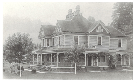 A black and white photo of a large Victorian-era house. 