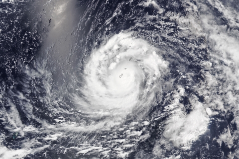 Satellite view of massive swirling storm over mostly ocean. 