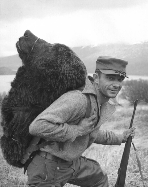 man with rifle and bear head strapped to his back