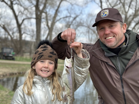 A child and a FWS employee hold up a fish that was caught.