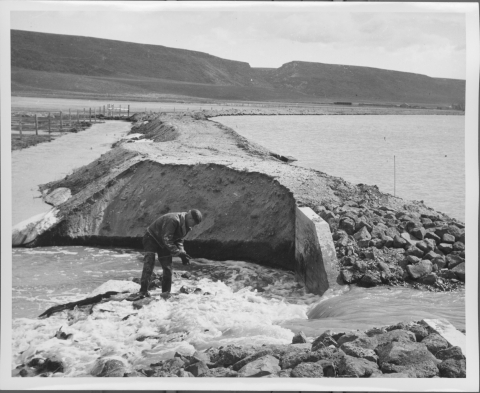 Man working in washed-out rip-rap on the edge of a spillway