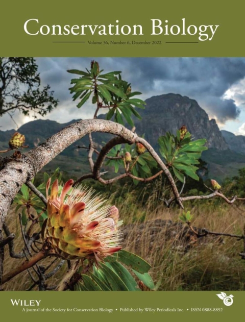 Cover of scientific journal, with "Conservation Biology" title along the top, an image of a tree branch with a flower and leaves in the middle, and text reading "Wiley, a journal of the society for conservation biology" along the bottom. 