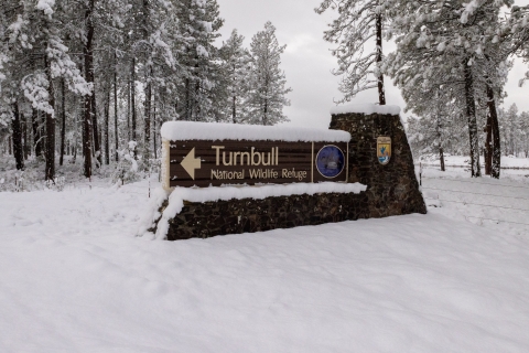 A refuge entrance sign covered in snow