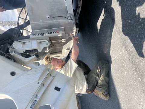 Watercraft inspector uses his finger to physically feel the drain hole of boat for aquatic invasive species.